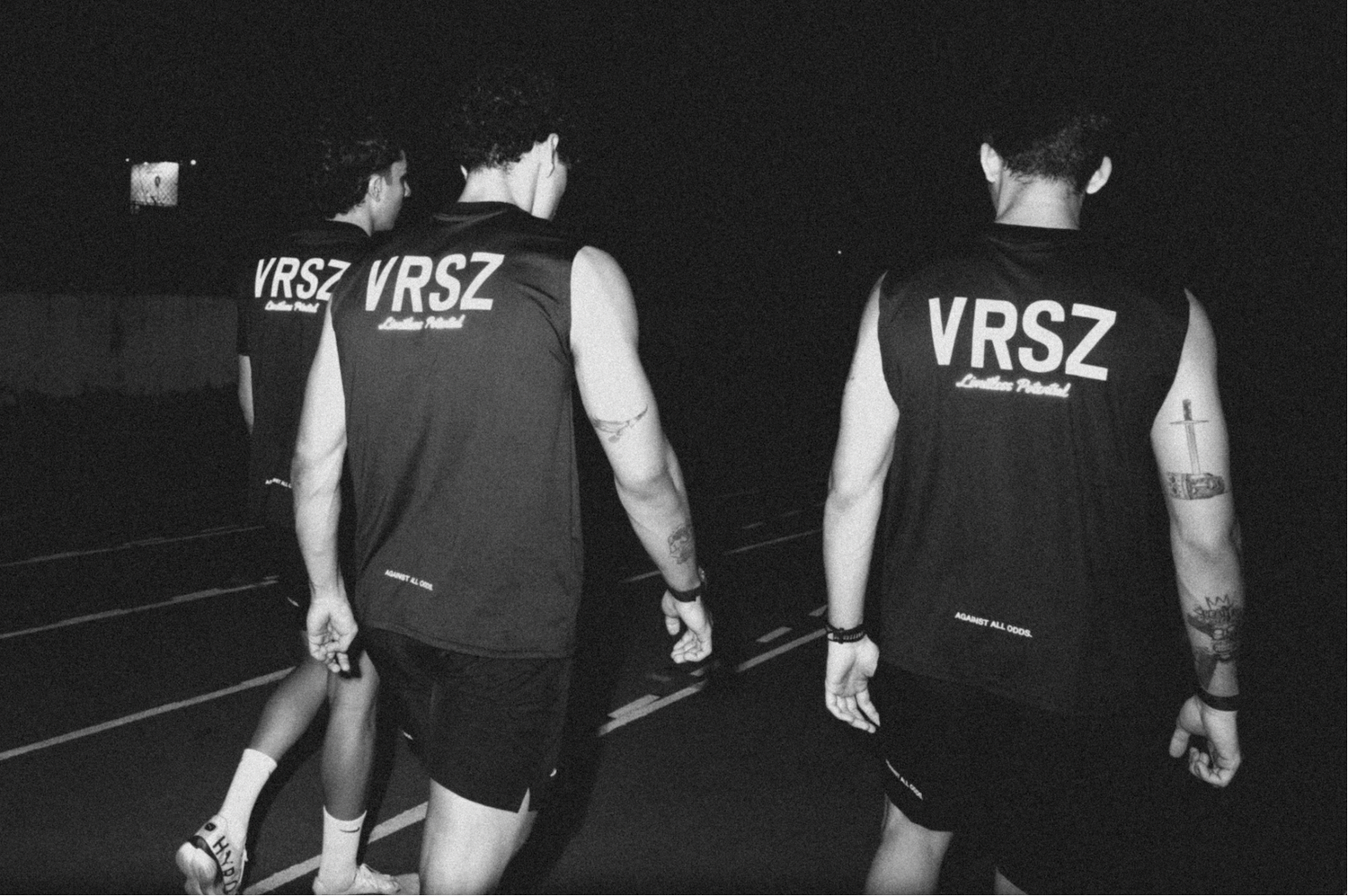 Three individuals wearing VRSZ vests walking on a track at night.